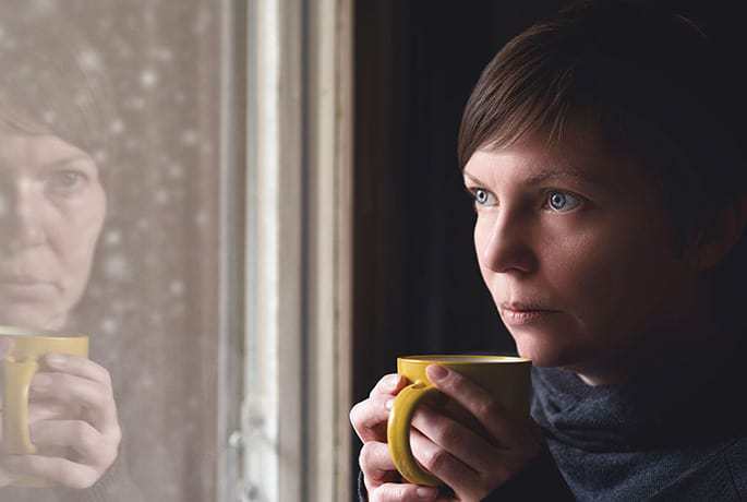 Women looking out window having recently lost someone to suicide