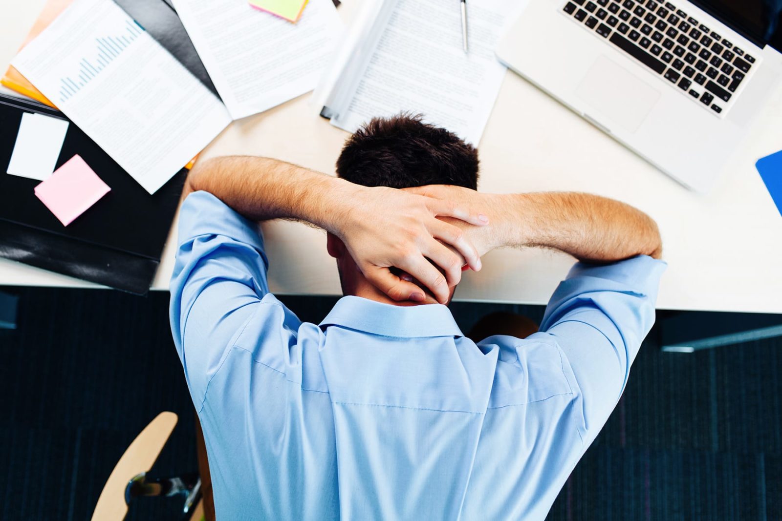 Man sat at desk, with his head in his hands trying to manage workplace stress