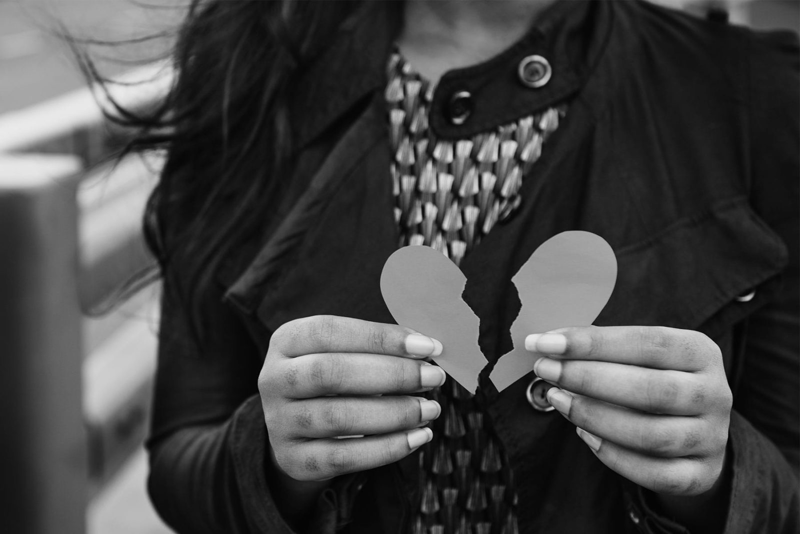 Women holding a piece of card in the shape of a broken heart