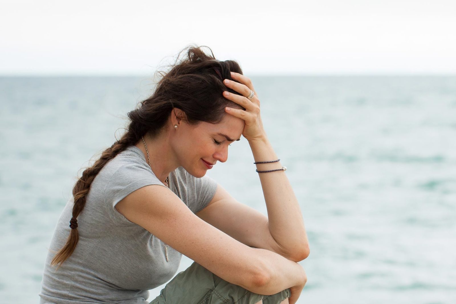 Women sat crying at the beach showing suicide warning signs