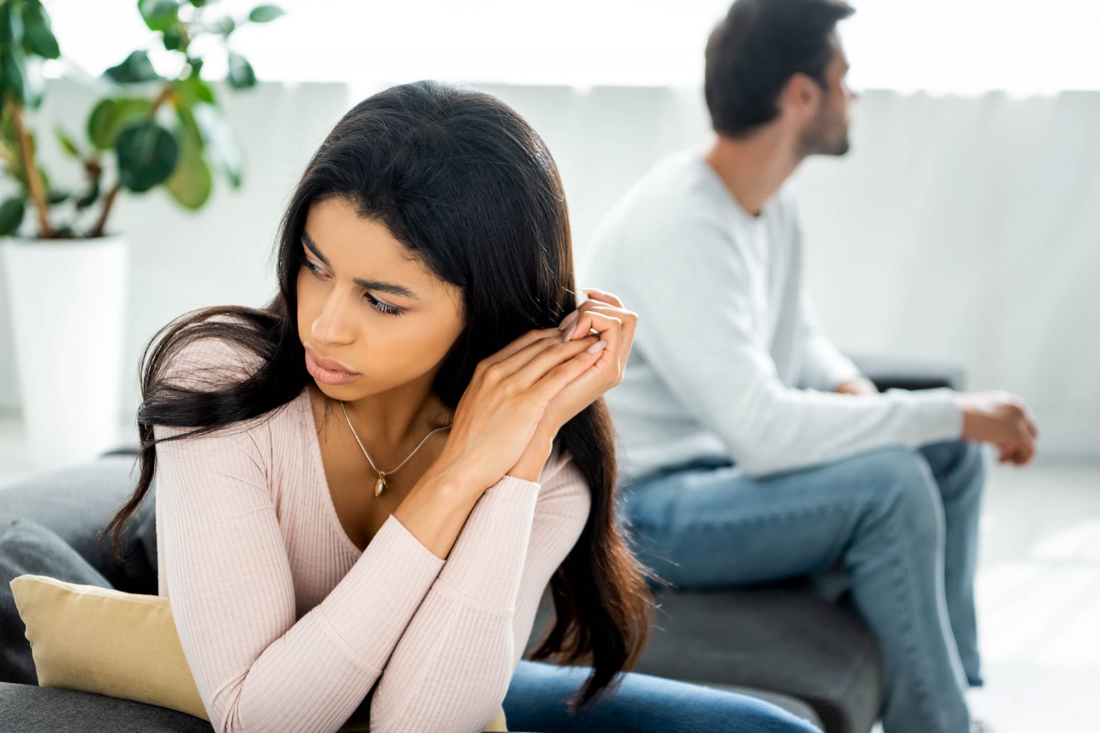 Unhappy couple sat on the end of a bed
