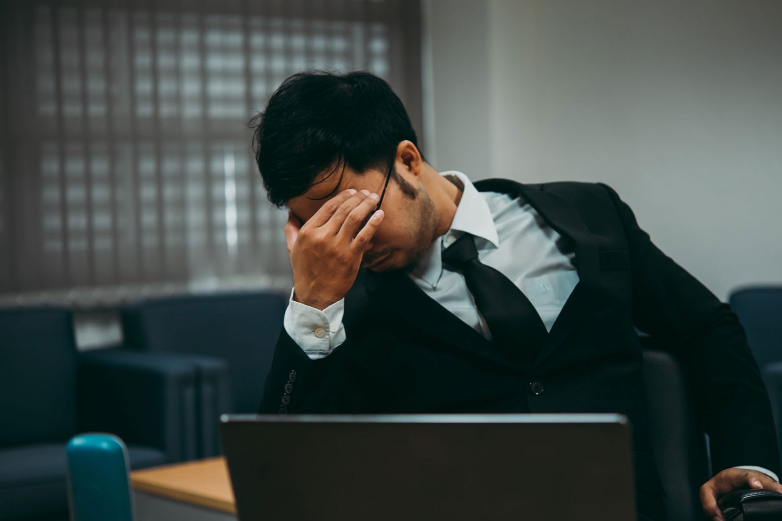 A man clearly stressed sat at a desk at work