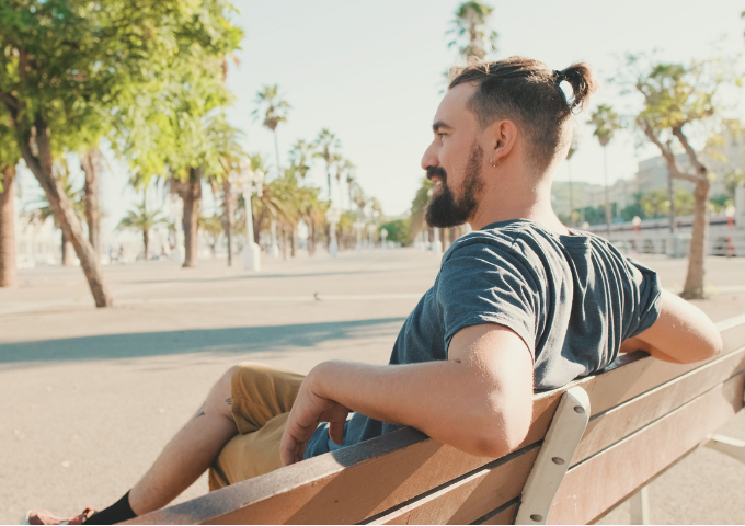 Young man sitting, resting on a bench