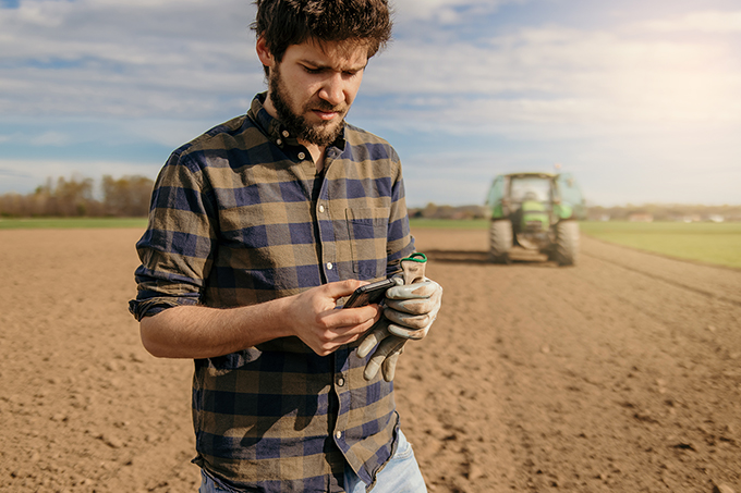 Young man on farm standing outside on phone