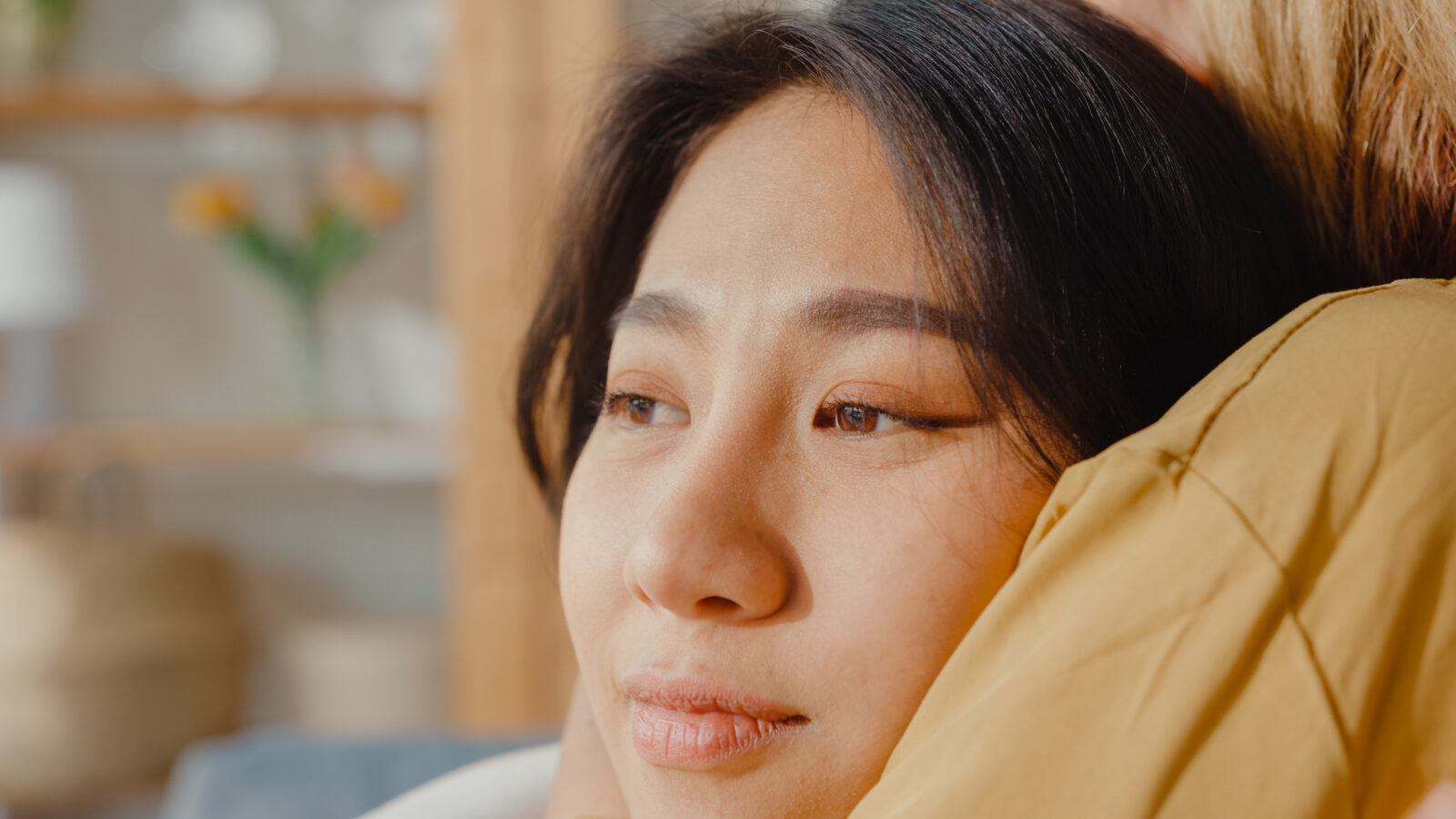Sad young asian woman hug cuddle embracing with best friend in living room at home support each other