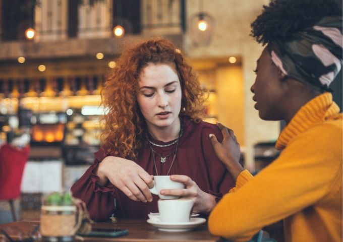Two female friends having a heartfelt conversation over coffee