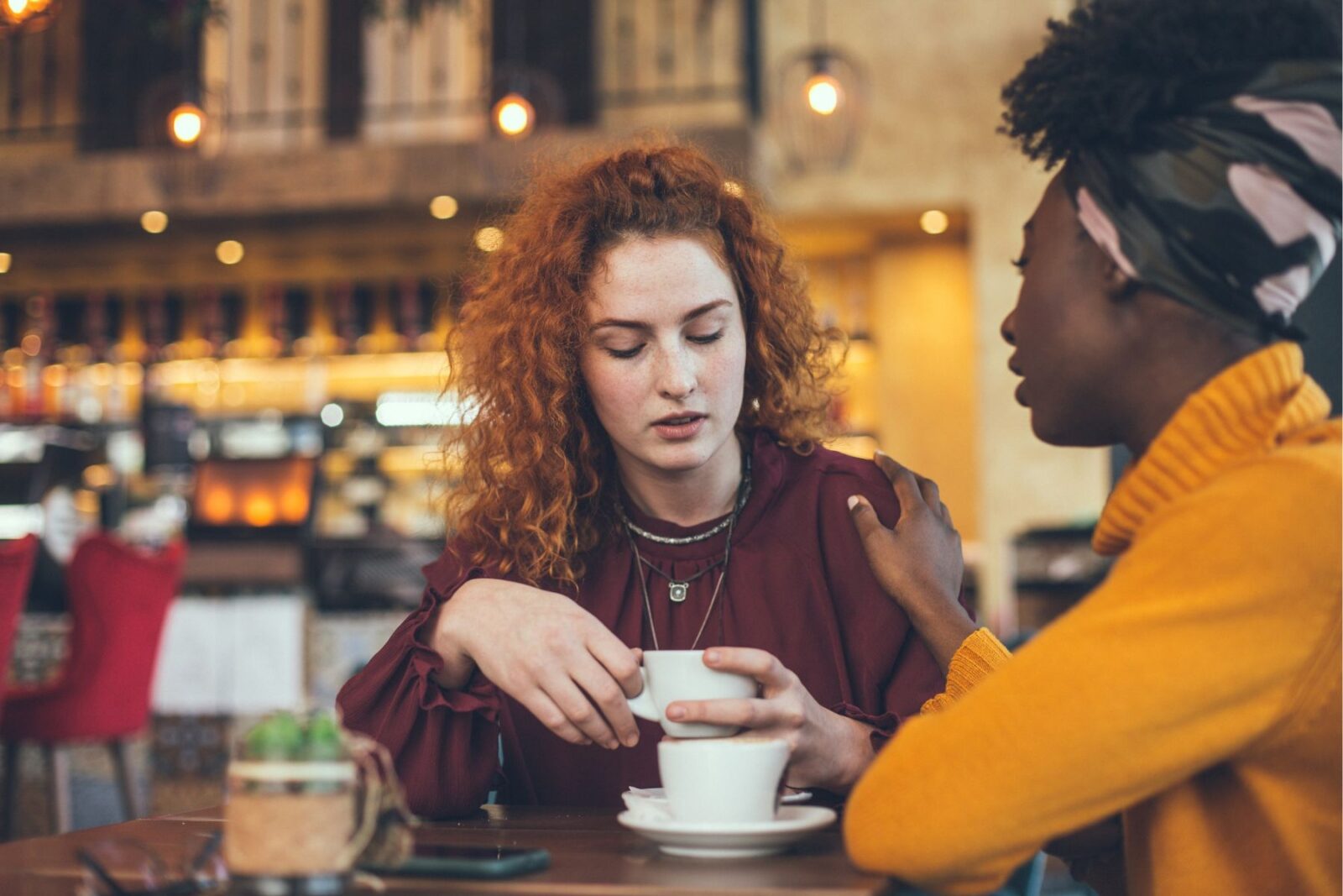 Two female friends having a heartfelt conversation over coffee